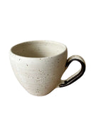 Speckled ceramic mug with a black handle on a white background