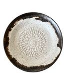 Ceramic plate with decorative brown rim and sunburst pattern on a white background
