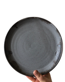 A set of handcrafted stoneware plates with a speckled brown finish and a bronze lip.