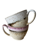 Two ceramic mugs stacked on a white background