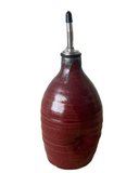 A beige, gray, and brown ceramic oil cruet with a spout and black accents on a white background.