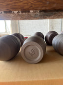 Trimmed pottery drying on a shelf for the bisque fire. 