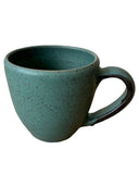 Teal ceramic mug with speckled texture on a white background