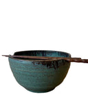 Blue ceramic bowl with wooden chopsticks on a white background