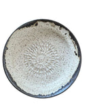 Ceramic plate with sunburst pattern on a white background