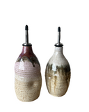 Two ceramic oil and vinegar bottles with speckled design on a white background