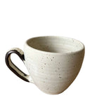 Speckled beige ceramic mug on a white background