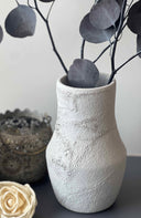 Textured white vase with eucalyptus branches on a neutral background