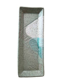 A rectangular ceramic dish with a speckled light gray and white glaze, featuring a light blue painted leaf design on the right side, set against a plain white background.
