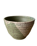 Green ceramic bowl with speckled texture on a white background