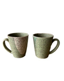 Two green ceramic mugs with speckled texture on a white background
