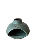 A teal palo santo burner on a white background. 