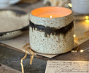 Ceramic candle on papers and table with christmas lights. 