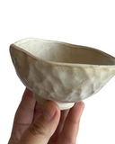 Hand holding a ceramic bowl with a textured surface on a white background