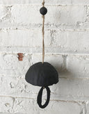 Black decorative item with a string against a white brick wall