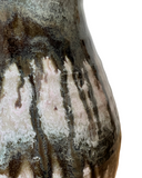 Close-up of a ceramic vase with textured surface and color variations on a white background