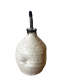 Speckled ceramic oil bottle with a black cap on a white background