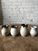 Row of ceramic pots with metallic bases on a textured surface