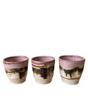 A photo of three ceramic cacao cups in beige, bronze, pink and gold. 