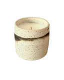 A candle with a beige and brown marbled ceramic container, featuring a single wick.