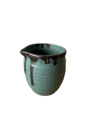 Teal ceramic pitcher with brown speckles on a white background