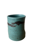 Teal ceramic cup with speckled texture on a white background