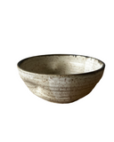 A stack of three handmade ceramic bowls in beige, gray, and purple colors.