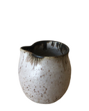 Ceramic pitcher with black interior on a white background
