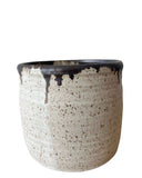 A beige and bronze ceramic utensil crock or vase on a white background. 