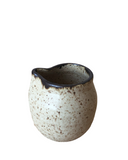 Speckled ceramic pitcher on a white background