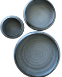 A set of three gray plates on a white background.
