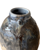 Rustic ceramic vase with textured surface on a white background