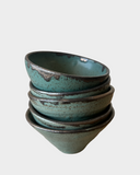Stack of teal ceramic bowls on a light gray background