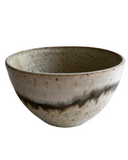 Ceramic bowl with speckled glaze on a white background