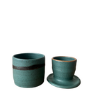 Two teal ceramic cups with brown accents on a white background