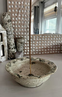 Ceramic bowl with incense stick on a textured wall background