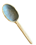 A handcrafted stoneware serving spoon with a beige color and speckled patterns.