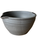 A handcrafted stoneware mixing bowl with a speckled brown and beige color and a bronze lip.