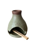 A green palo santo burner on a white background. 