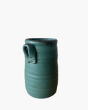 Green ceramic vase with a handle on a white background