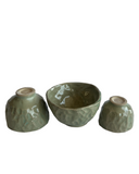 Three green ceramic bowls with textured surfaces on a white background
