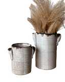 Two Luna Utensil Holders, one small holding a wine bottle and the other large with wooden utensils, both in a beige color with stamped handles.