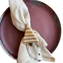 Napkin tied with a decorative triangle napkin holder on a maroon plate.