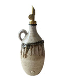 An olive oil pourer and bottle in beige, bronze and gold on a white background. 