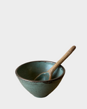 Ceramic bowl with a wooden spoon on a light gray background