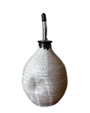 White ceramic oil dispenser with black speckles on a white background