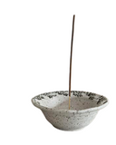 Ceramic incense holder with a single incense stick on a white background