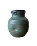 A teal and bronze vase on a white background. The vase has a thumprint. 