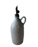Gray oil bottle with a black weighted spout on a white background. 