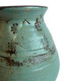 Turquoise ceramic vase with brown abstract patterns on a white background